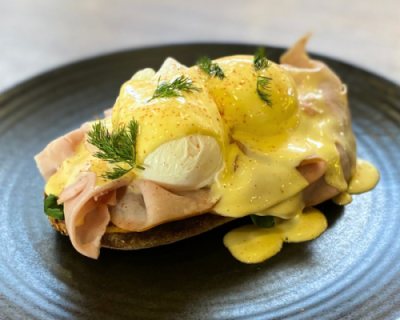 Close up eggs benedict on black plate