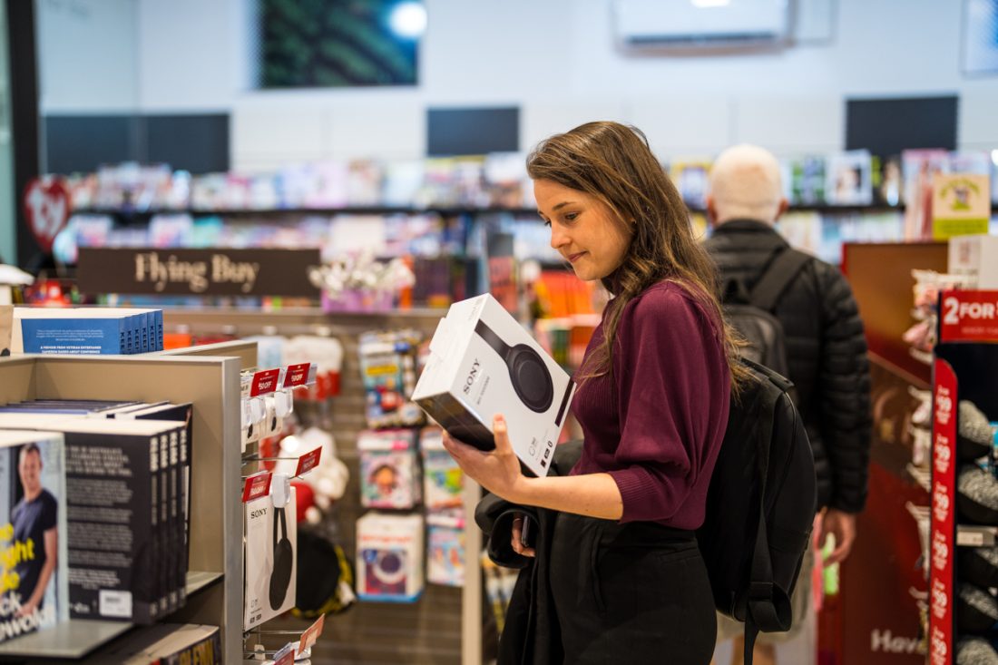 Woman shopping in retail store showing books and headphones.